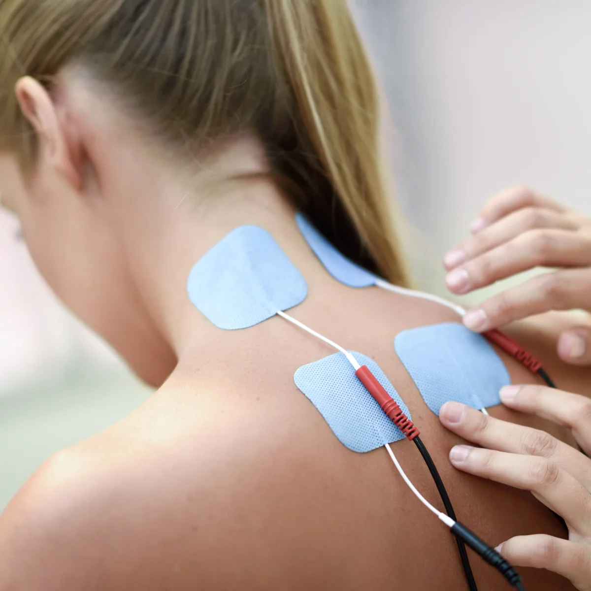 Elektroden an Nacken und Schulter einer Patientin, Elektrotherapie