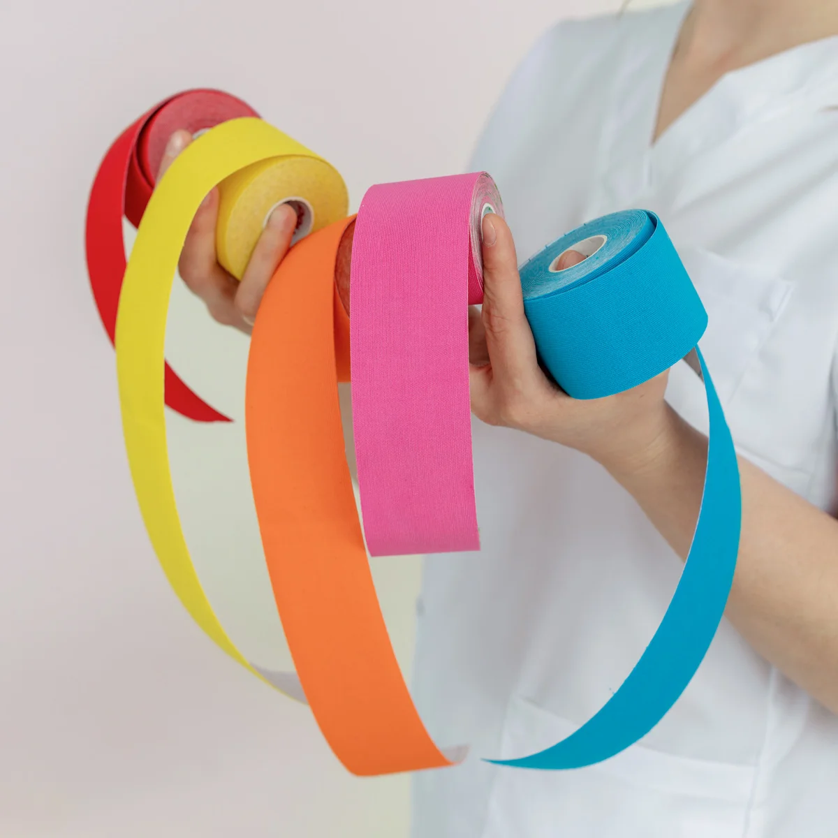 Physiotherapeutin hält bunte Rollen Kinesio-Tape Elektroden (javiindy): Elektroden an Nacken und Schulter einer Patientin, Elektrotherapie