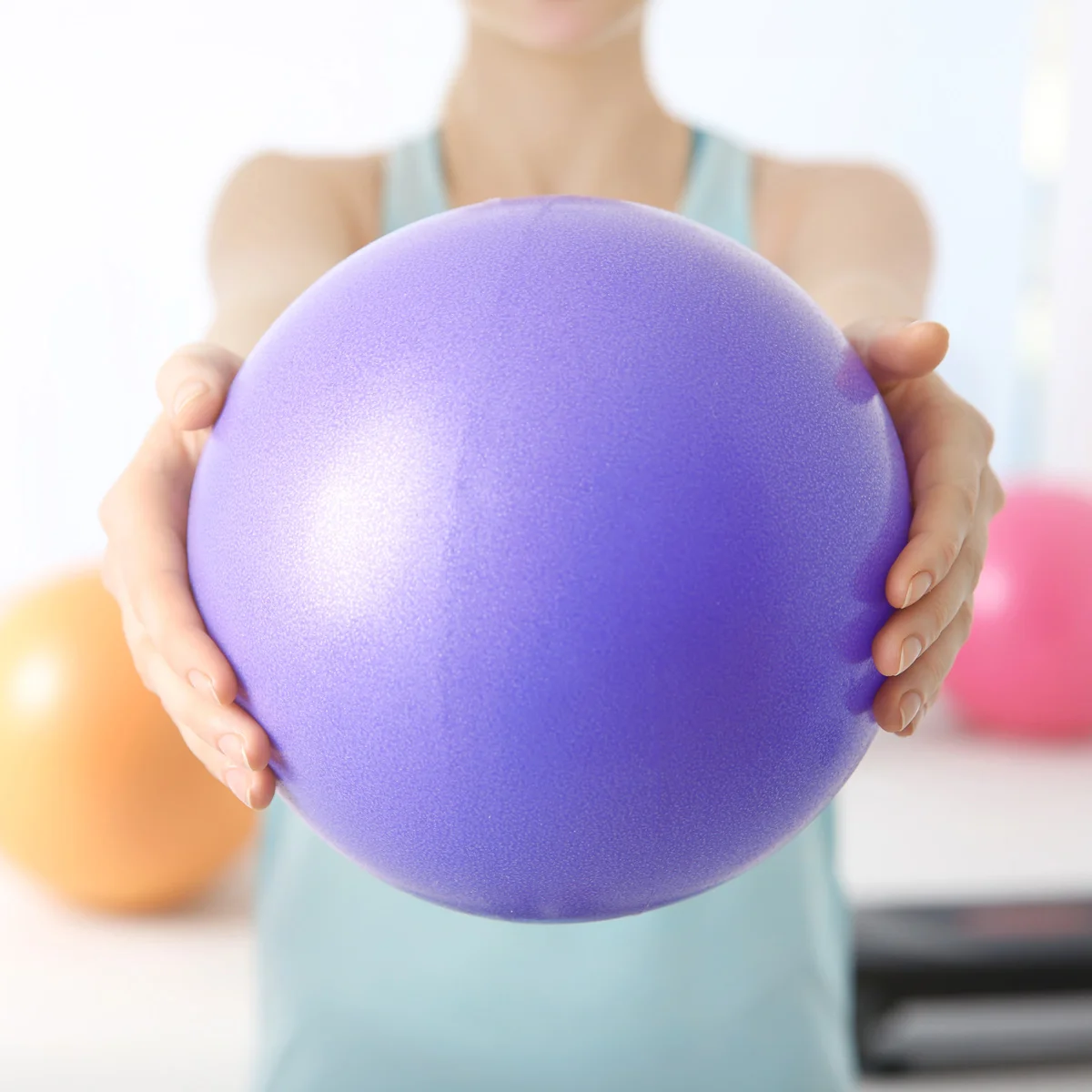 Frau hält einen kleinen Gymnastikball, Übung zur Kräftigung in der Physiotherapie