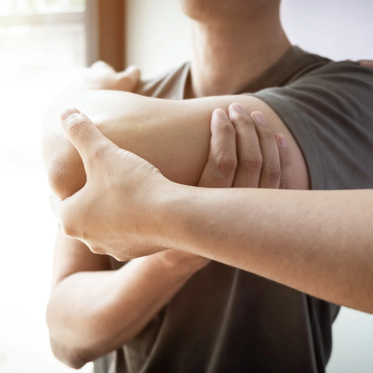Physiotherapeutin mobilisiert Schulter und Oberarm eines Patienten, Manuelle Therapie in Tessin